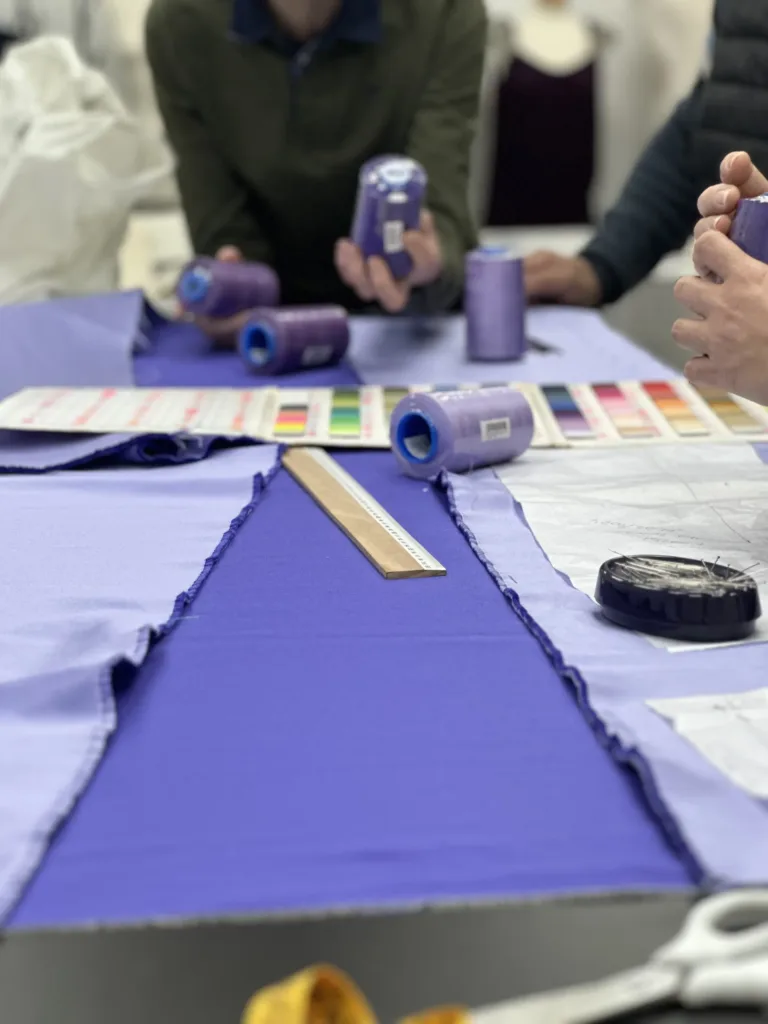 Alumnos de la Academia Studio19 en Murcia trabajando en clase de moda con telas moradas, hilos y patrones de confección