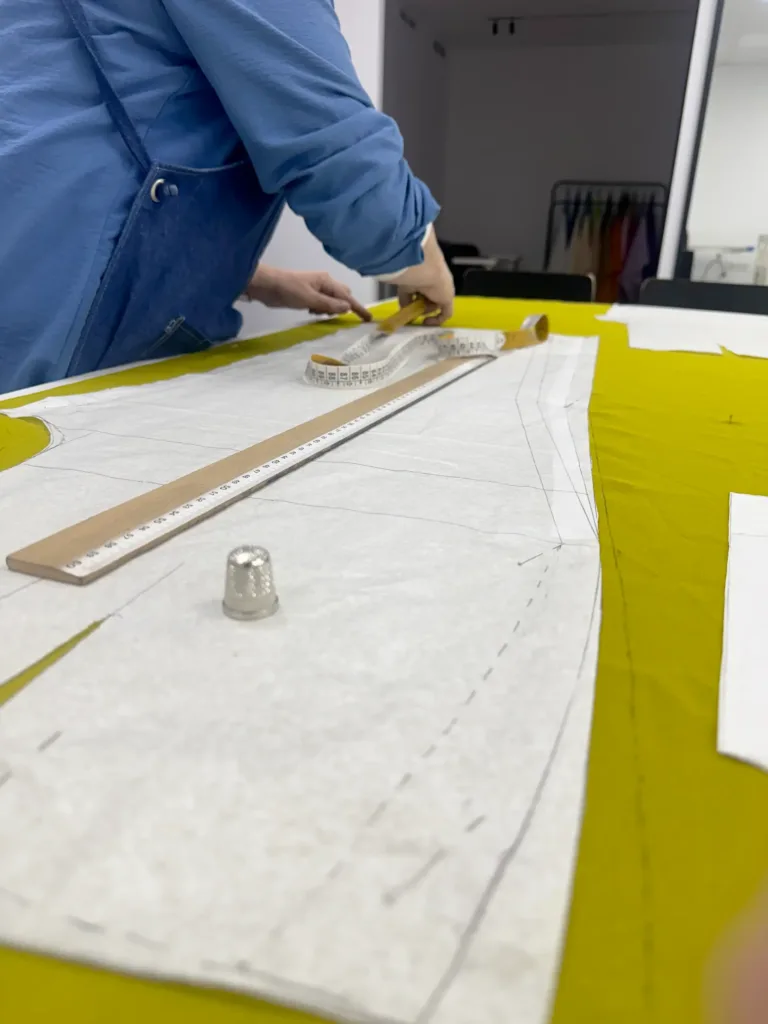 Alumno de la Academia Studio19 en Murcia trabajando con patrones de costura sobre tela amarilla en clase de patronaje y confección
